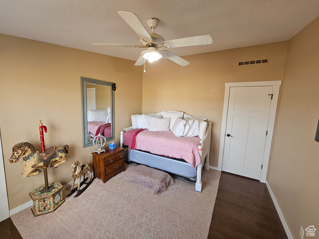 Bedroom with wood finished floors, baseboards, ceiling fan, and visible vents