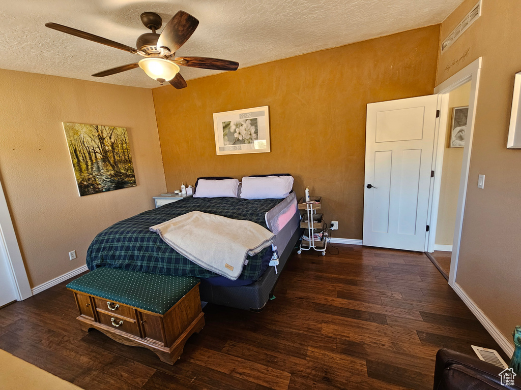 Bedroom featuring a ceiling fan, a textured ceiling, baseboards, and wood finished floors