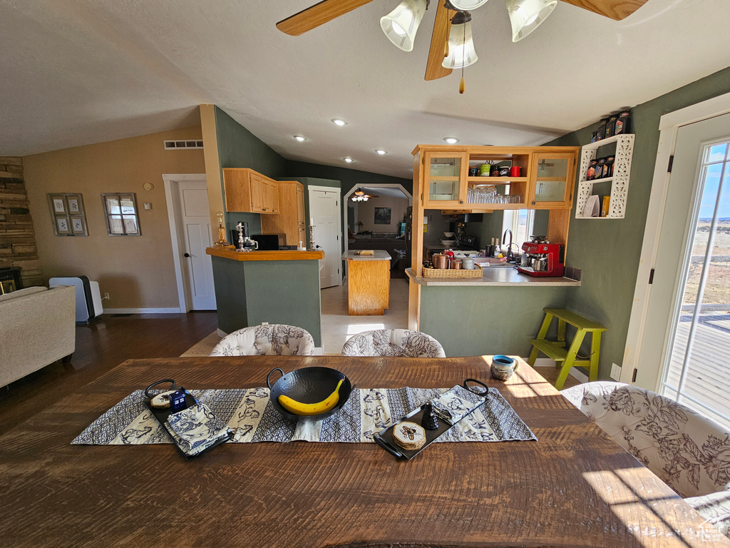 Dining space featuring lofted ceiling, baseboards, visible vents, a ceiling fan, and wood finished floors