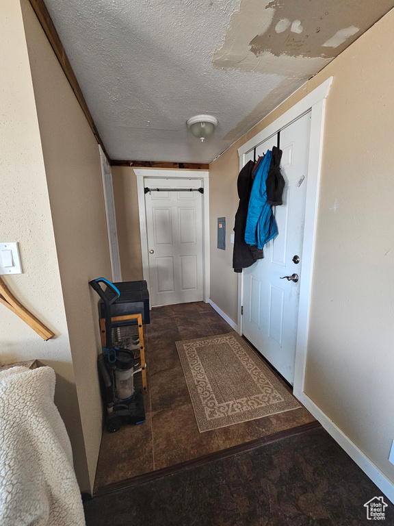 Doorway with baseboards, stone finish flooring, and a textured ceiling