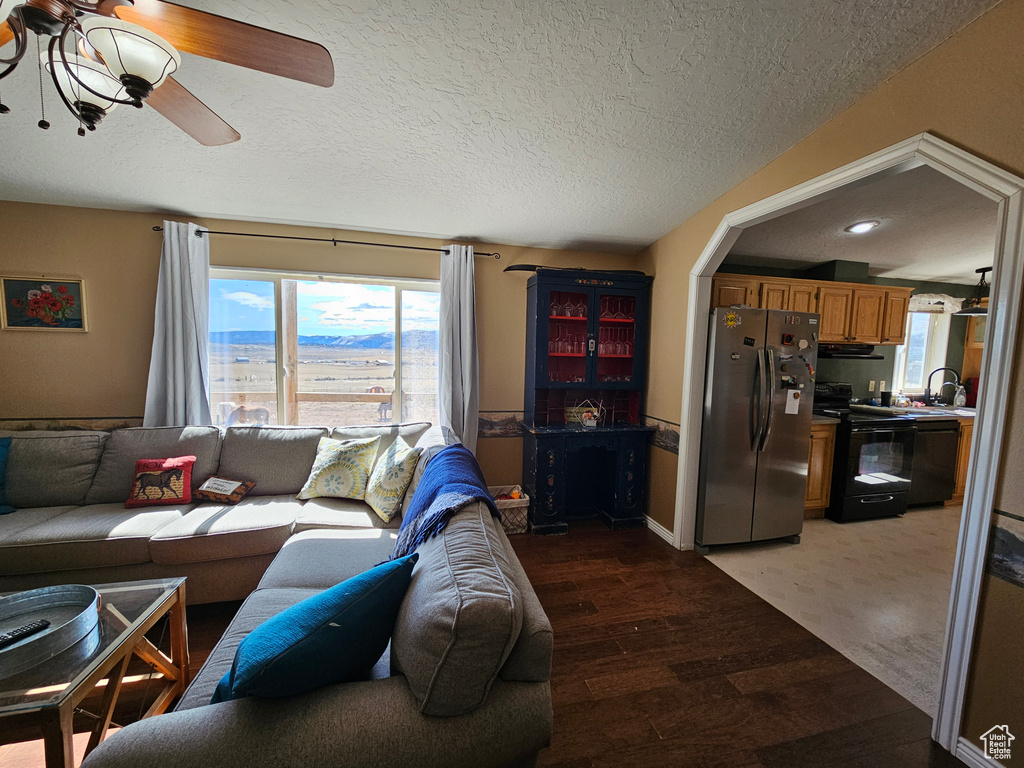 Living area featuring a ceiling fan, light wood-style floors, and a textured ceiling