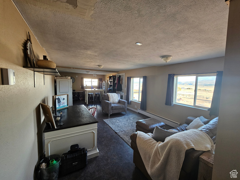Living room featuring baseboards, carpet floors, a textured ceiling, and baseboard heating