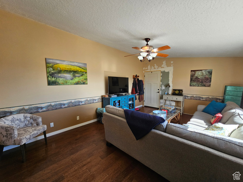 Living room featuring a textured ceiling, wood finished floors, baseboards, and a ceiling fan