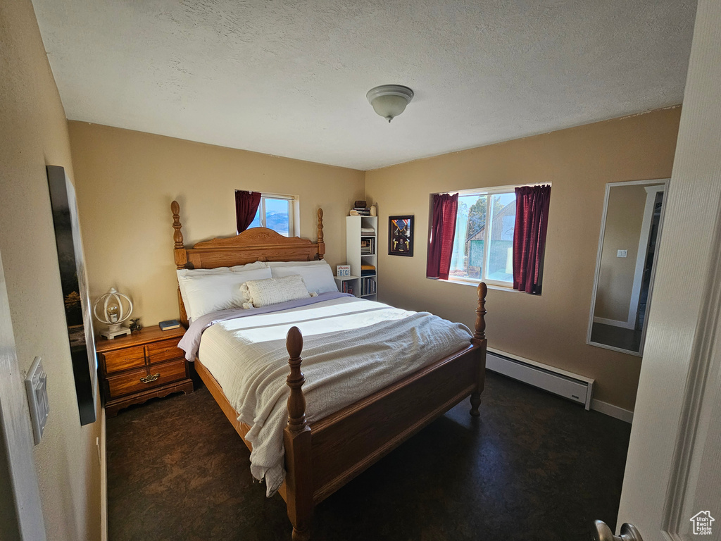 Bedroom featuring baseboard heating and a textured ceiling