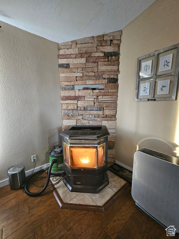 Details featuring baseboards, wood finished floors, a wood stove, and a textured ceiling