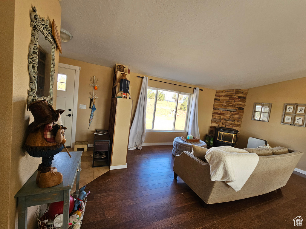 Living room featuring a stone fireplace, baseboards, hardwood / wood-style flooring, and a textured ceiling