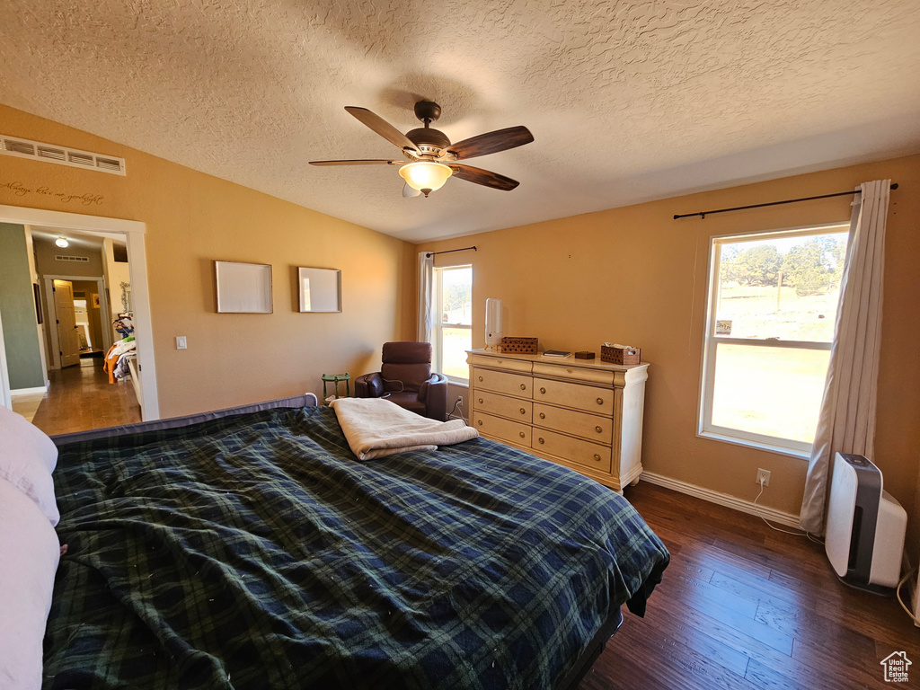 Bedroom with visible vents, baseboards, wood finished floors, a ceiling fan, and vaulted ceiling