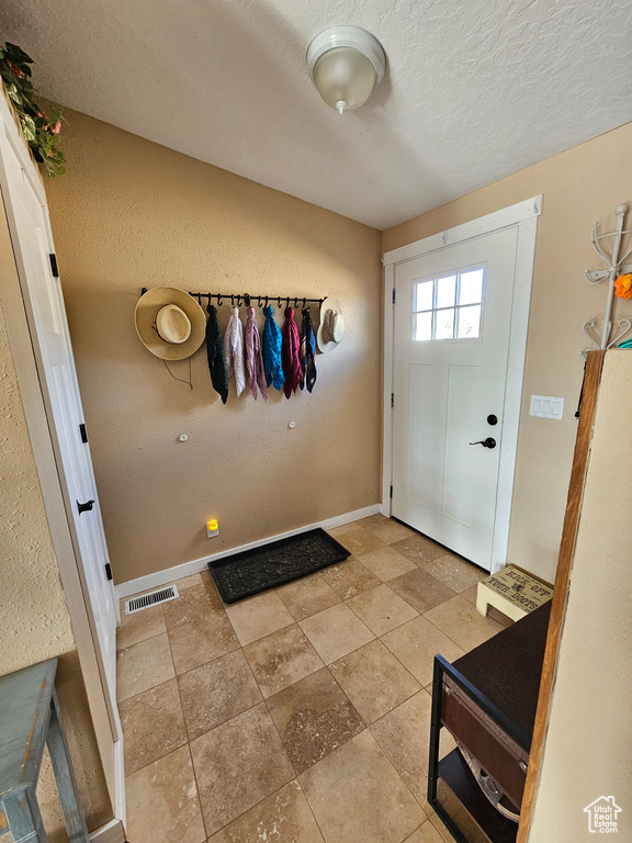Entryway with baseboards, a textured ceiling, and visible vents