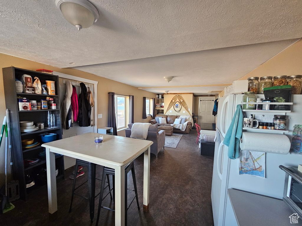 Dining space featuring dark carpet and a textured ceiling