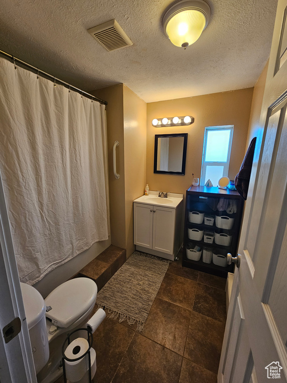 Full bathroom featuring toilet, curtained shower, vanity, a textured ceiling, and visible vents