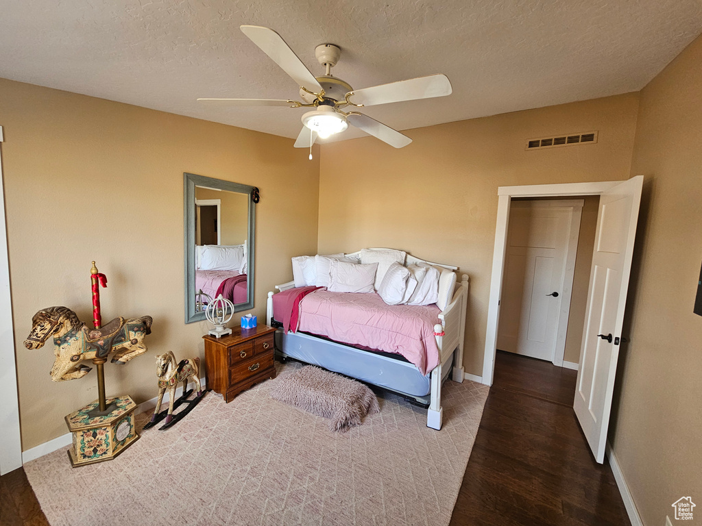 Bedroom with baseboards, a textured ceiling, visible vents, and wood finished floors