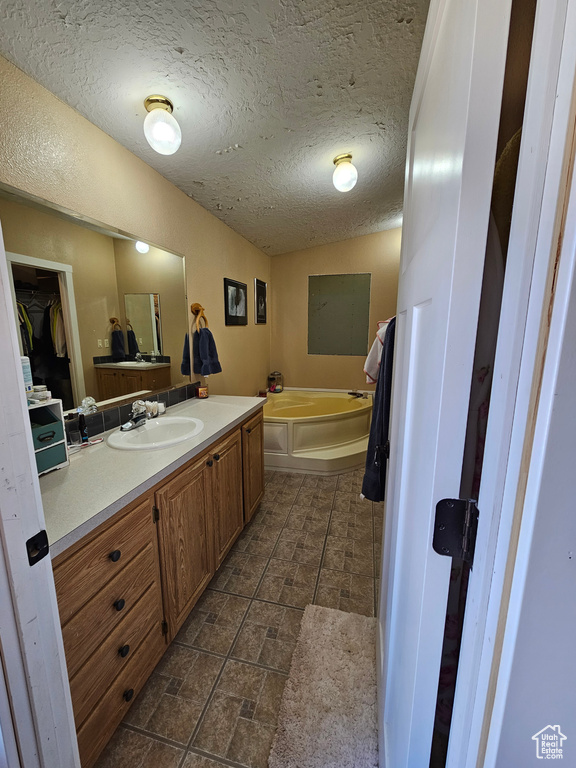 Bathroom with a textured ceiling, a garden tub, and vanity