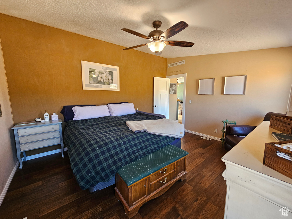 Bedroom with dark wood finished floors, baseboards, a ceiling fan, and a textured ceiling