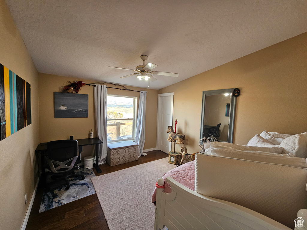 Bedroom with dark wood-style flooring, a textured ceiling, baseboards, a ceiling fan, and lofted ceiling
