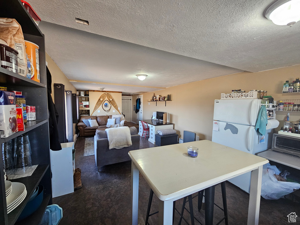 Kitchen with a textured ceiling and freestanding refrigerator