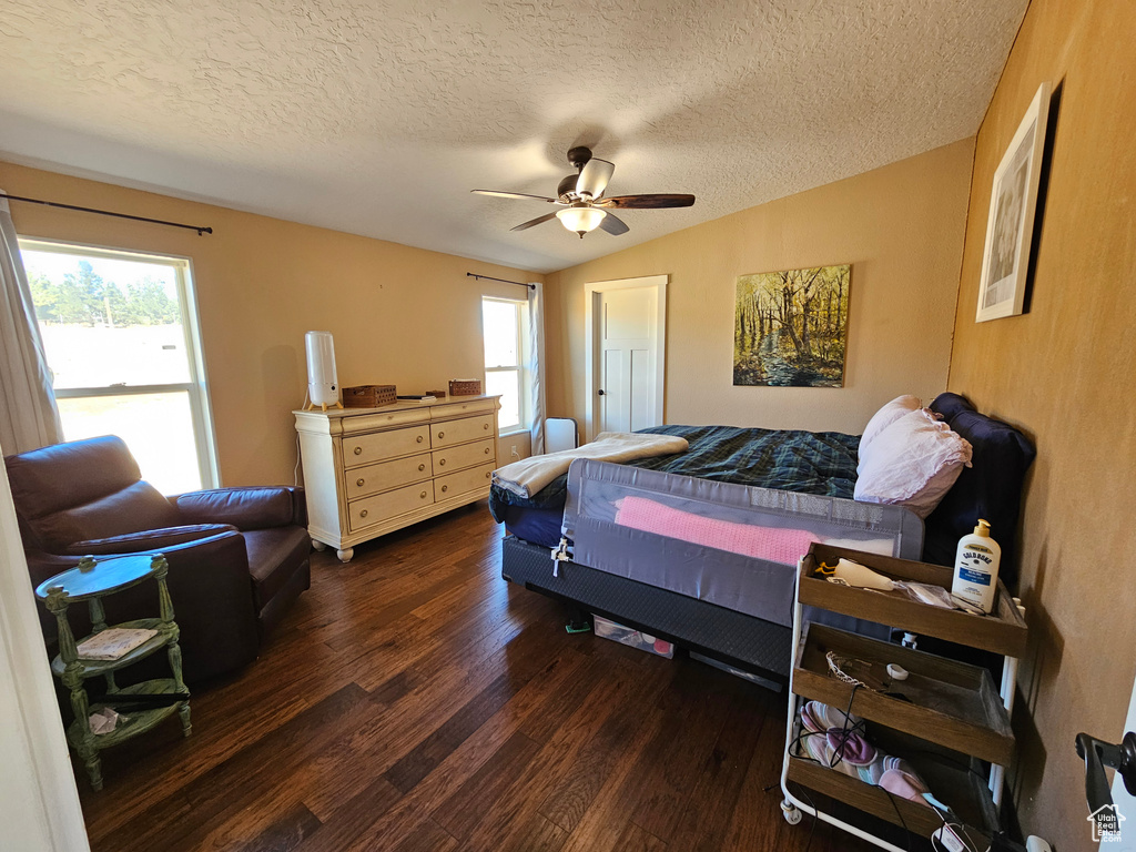 Bedroom featuring lofted ceiling, wood finished floors, ceiling fan, and a textured ceiling