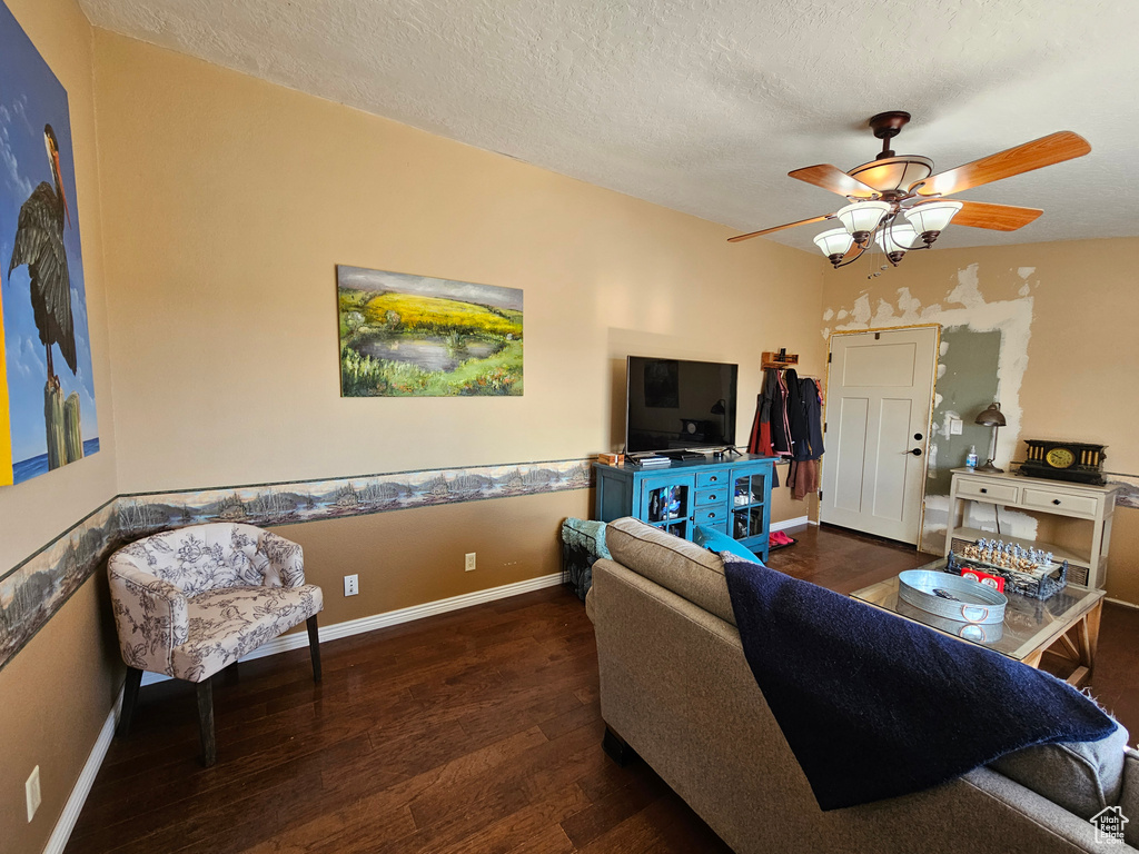 Living area featuring baseboards, a textured ceiling, ceiling fan, and wood finished floors