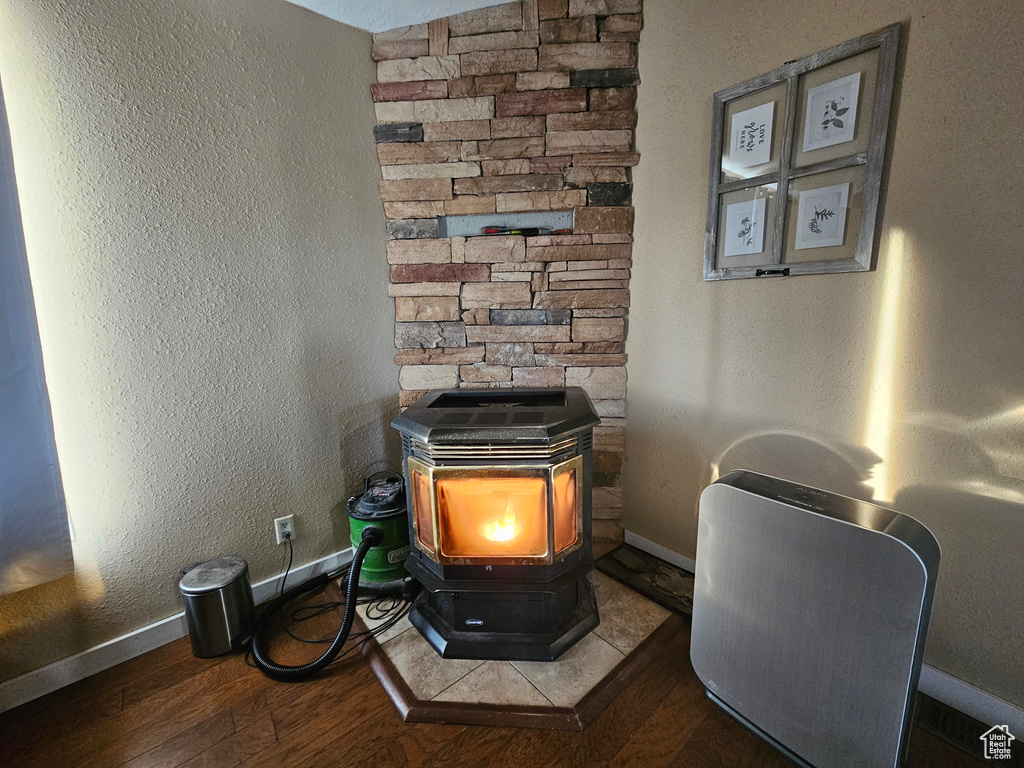 Interior details featuring baseboards, a textured wall, wood finished floors, and a wood stove