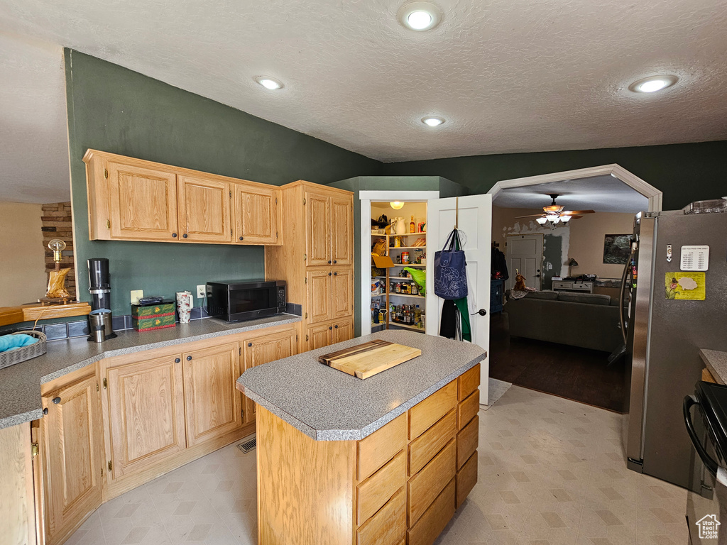Kitchen featuring light brown cabinetry, light floors, a ceiling fan, and freestanding refrigerator