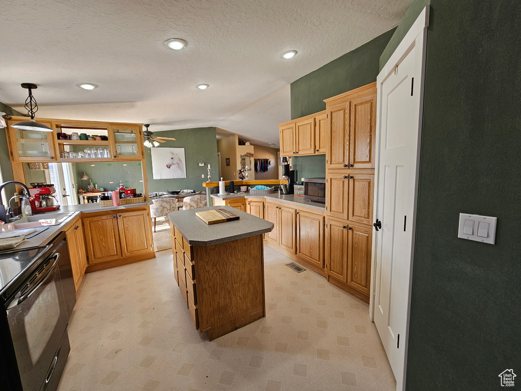 Kitchen with vaulted ceiling, a sink, a ceiling fan, a peninsula, and visible vents