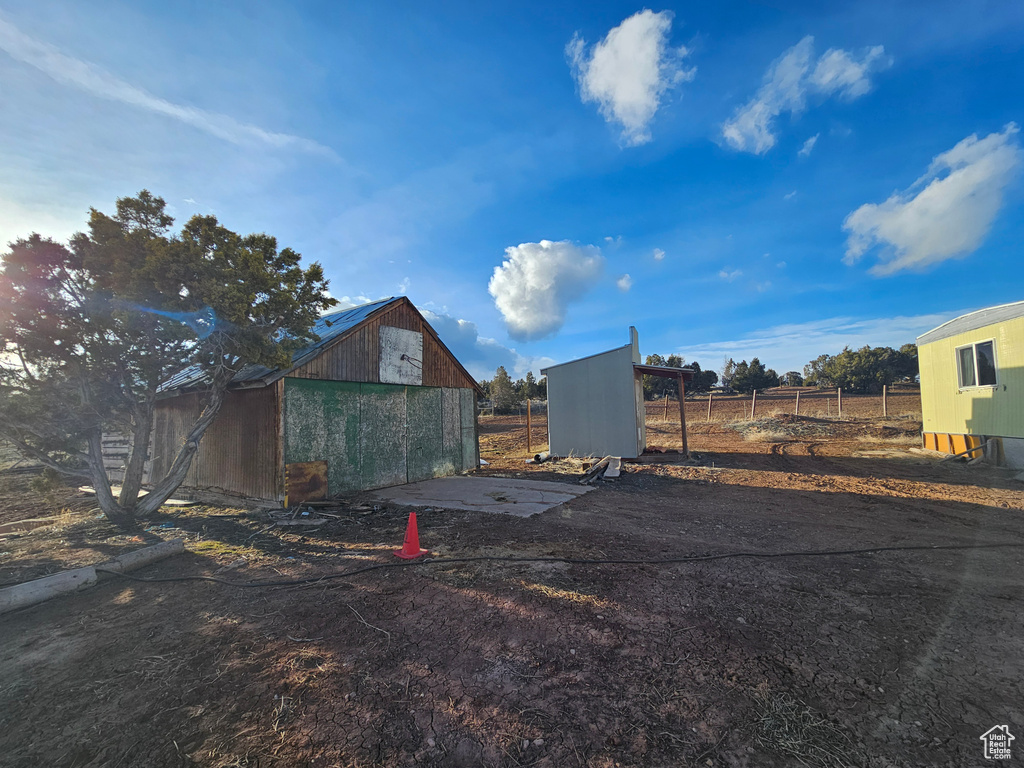 Exterior space with driveway, an outbuilding, and fence