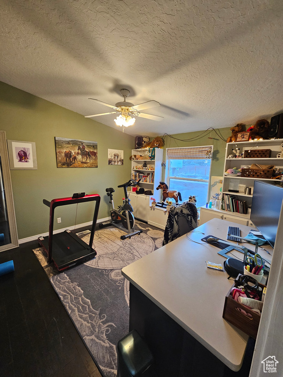 Home office with a textured ceiling, baseboards, ceiling fan, wood finished floors, and lofted ceiling
