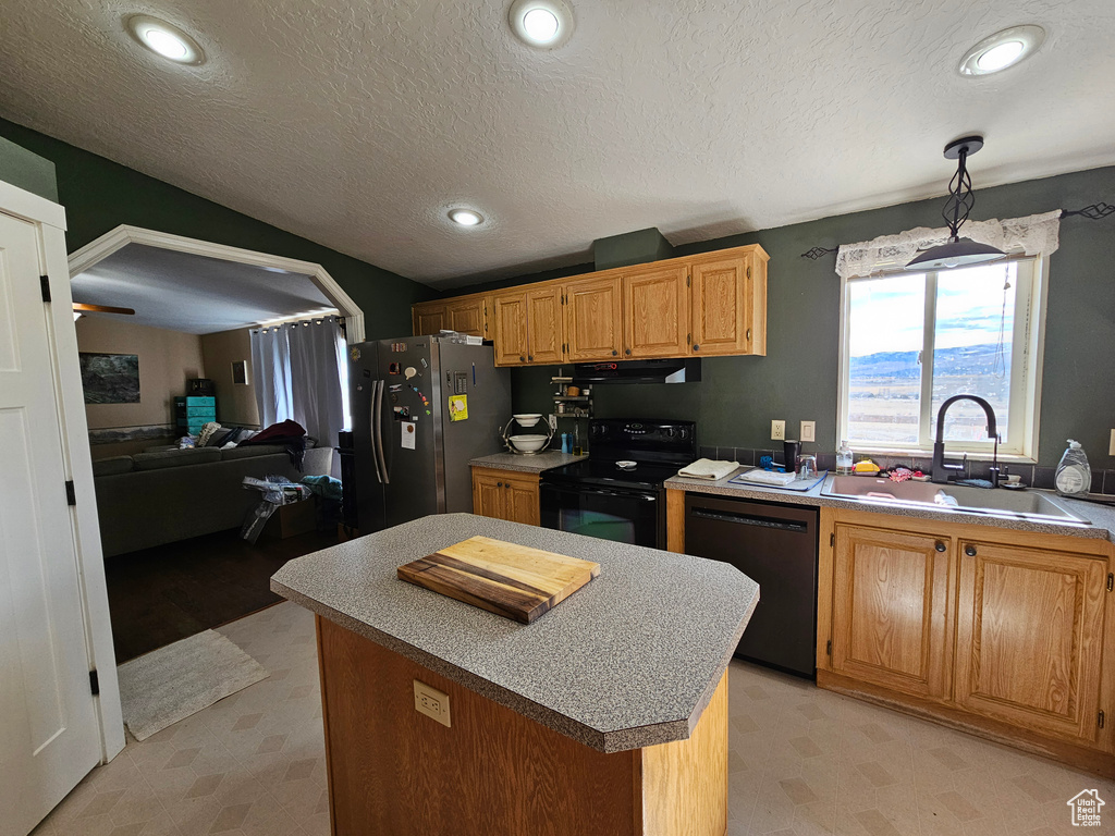 Kitchen with a sink, a kitchen island, light floors, black appliances, and recessed lighting