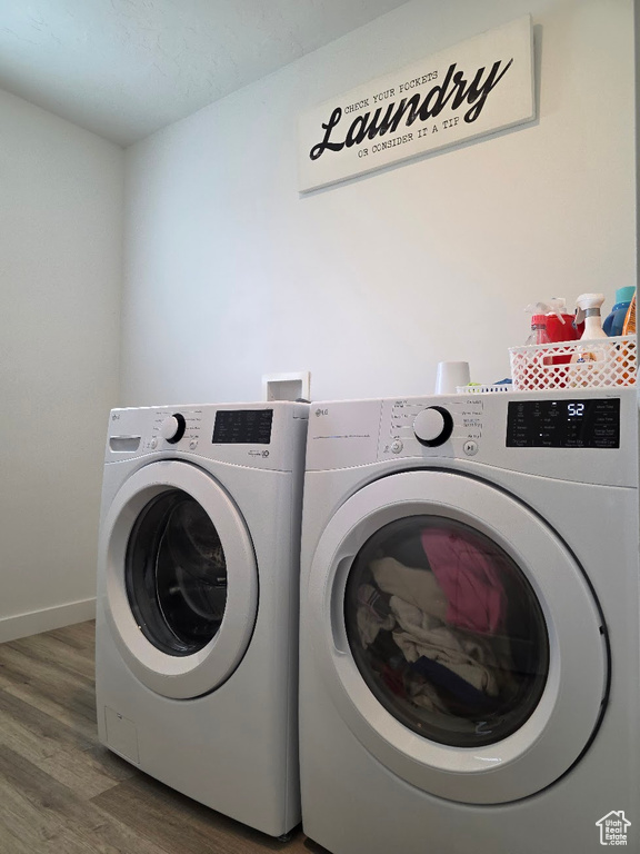 Washroom featuring separate washer and dryer, baseboards, laundry area, and wood finished floors