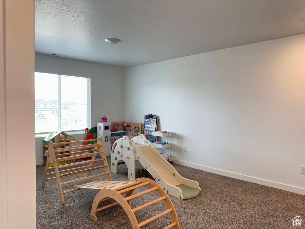 Rec room featuring baseboards, carpet flooring, and a textured ceiling