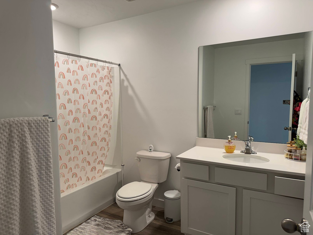 Full bath featuring toilet, vanity, shower / bath combo, and wood finished floors