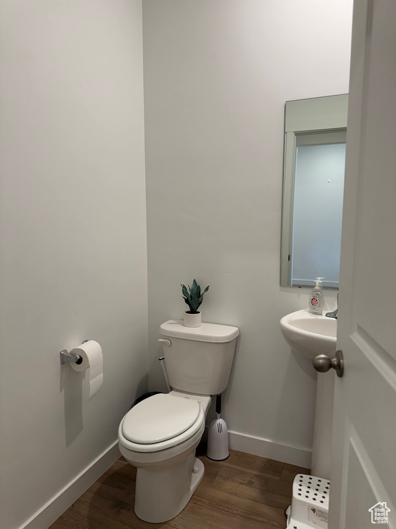 Half bath featuring baseboards, toilet, and wood finished floors