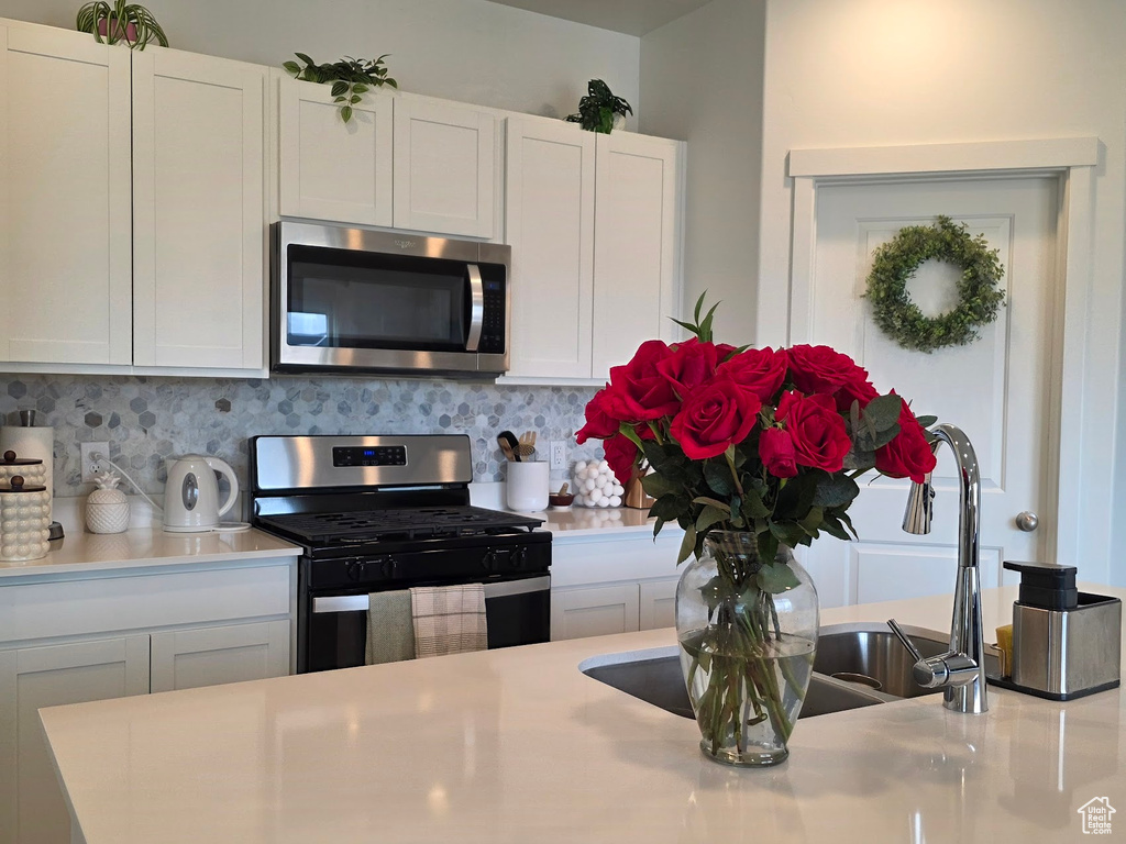 Kitchen with white cabinetry, light countertops, tasteful backsplash, and appliances with stainless steel finishes