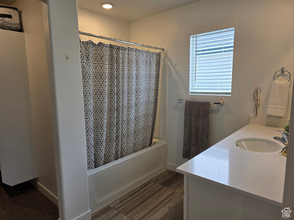 Full bath featuring wood finished floors, shower / tub combo with curtain, and vanity