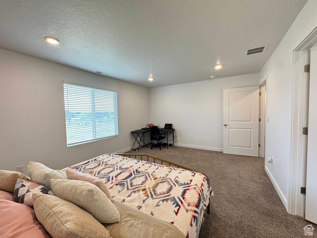 Bedroom featuring baseboards, visible vents, carpet flooring, and a textured ceiling