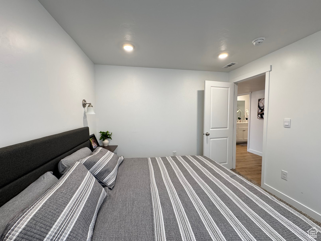 Bedroom with baseboards, visible vents, and wood finished floors