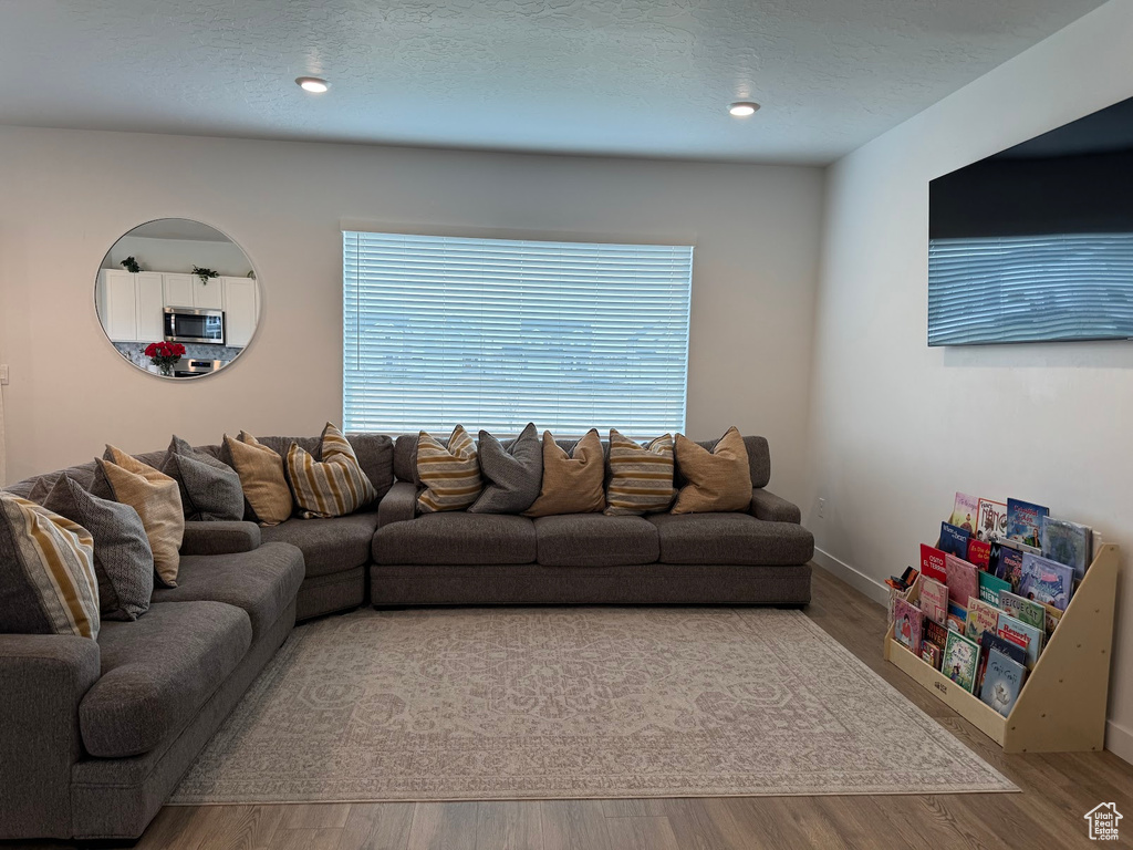 Living area with baseboards, wood finished floors, and a textured ceiling