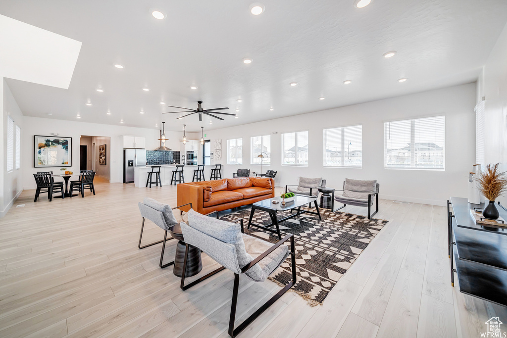 Living area with light wood-type flooring, baseboards, ceiling fan, and recessed lighting