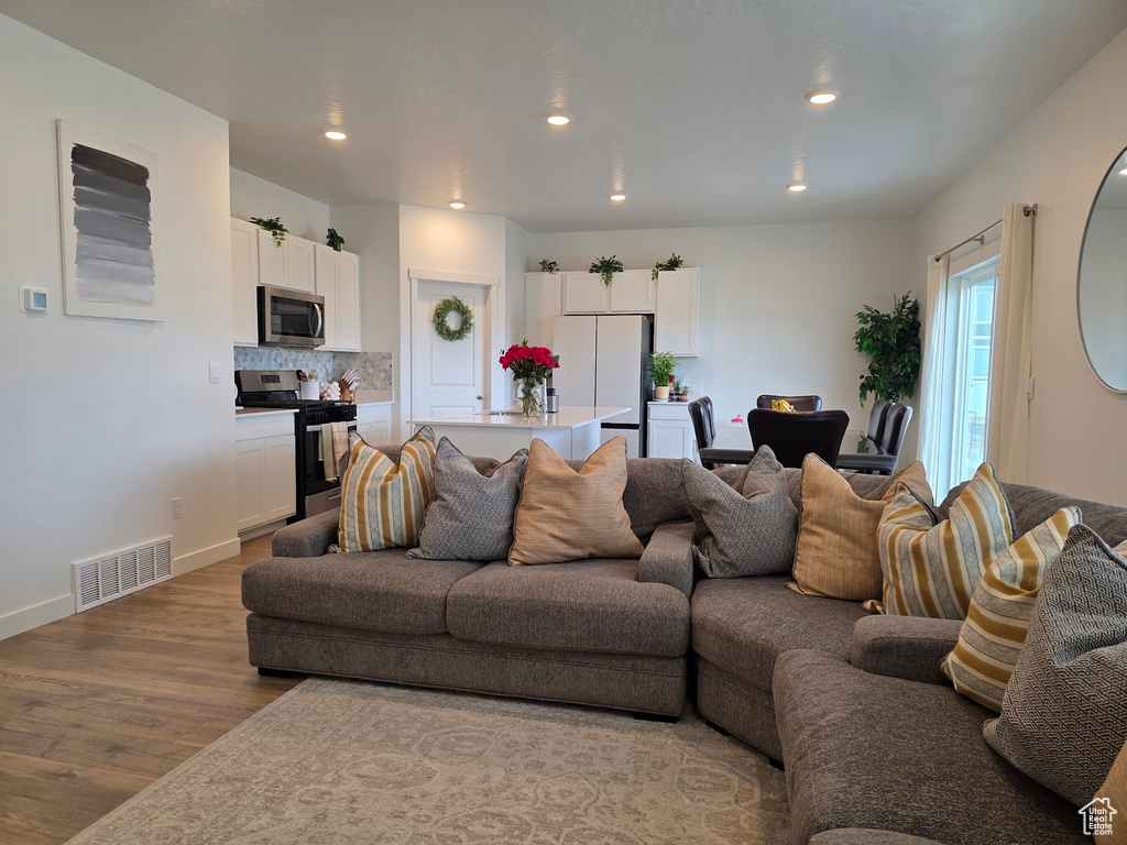 Living room featuring baseboards, visible vents, wood finished floors, and recessed lighting