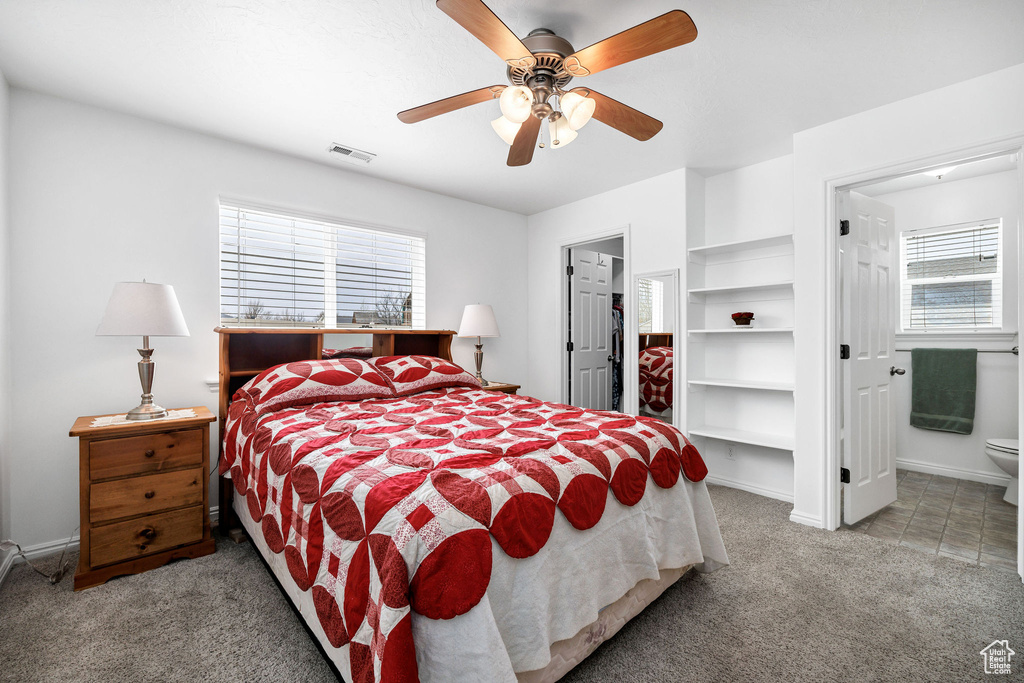 Carpeted bedroom featuring baseboards, visible vents, a spacious closet, and a ceiling fan