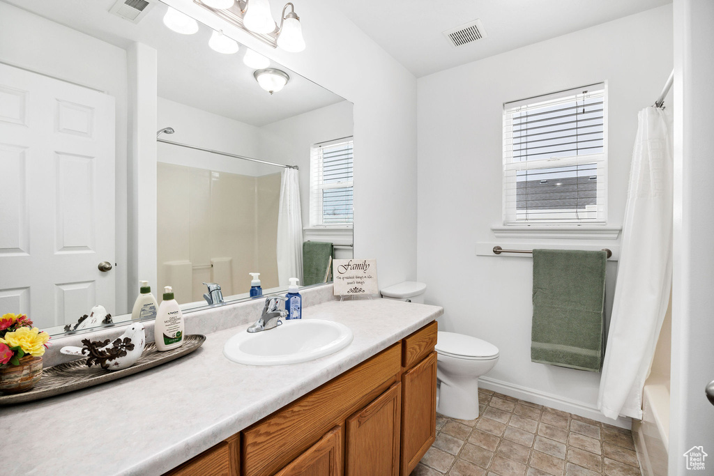 Bathroom featuring visible vents, toilet, vanity, and curtained shower
