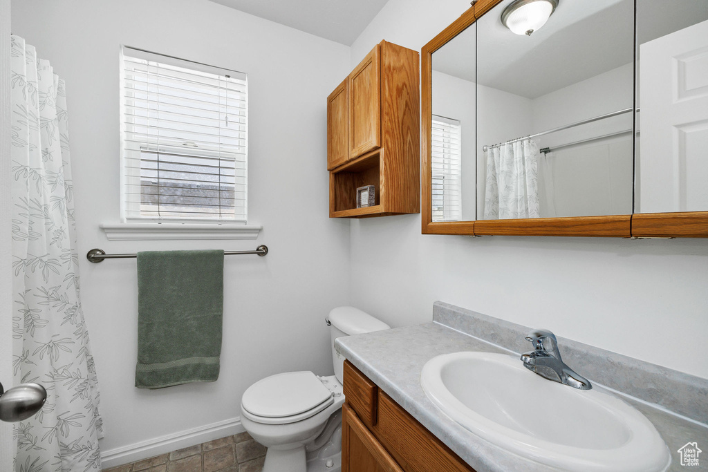 Full bathroom featuring baseboards, a shower with shower curtain, toilet, and vanity
