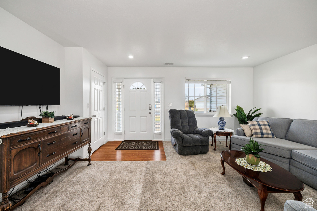 Living room with baseboards, visible vents, recessed lighting, and light colored carpet
