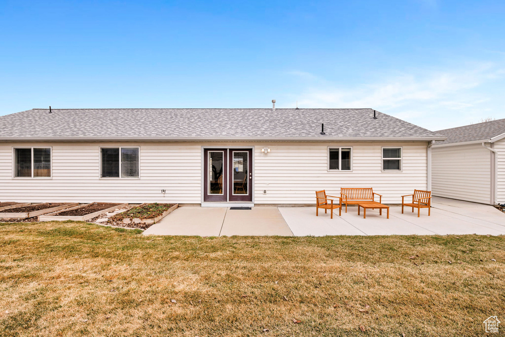 Rear view of house featuring roof with shingles, a yard, and a patio