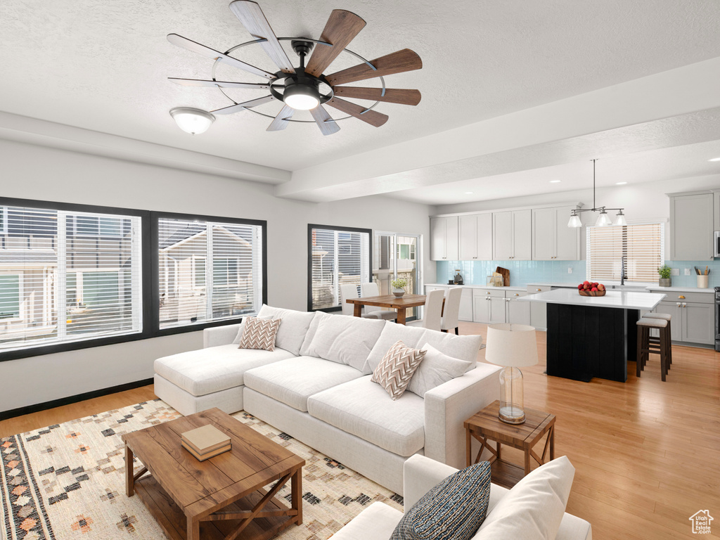 Living area featuring light wood-style floors, healthy amount of natural light, ceiling fan, and recessed lighting