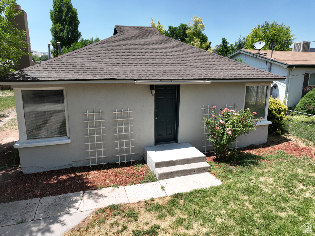 View of front facade featuring a shingled roof and stucco siding