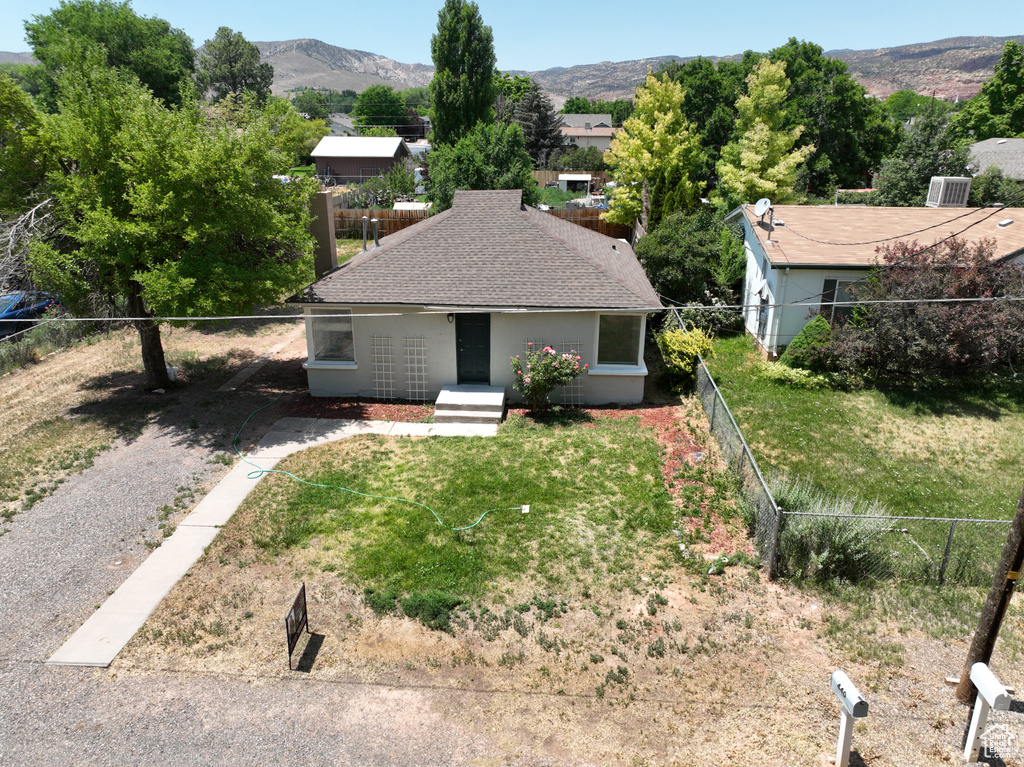 View of front facade with a fenced backyard, a mountain view, and roof with shingles