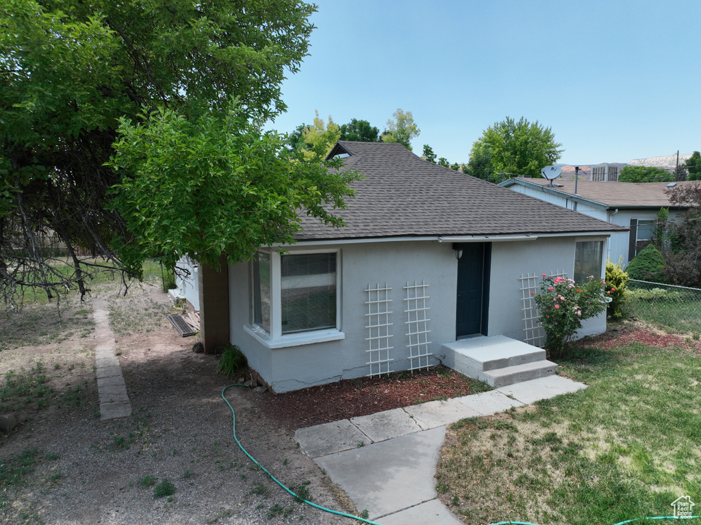 View of front facade with roof with shingles and stucco siding