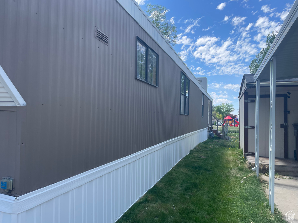 View of side of property featuring a lawn, a shed, and an outbuilding