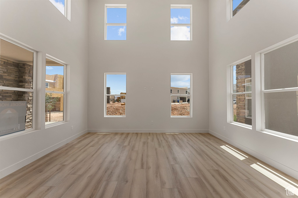 Empty room featuring a towering ceiling and light wood finished floors