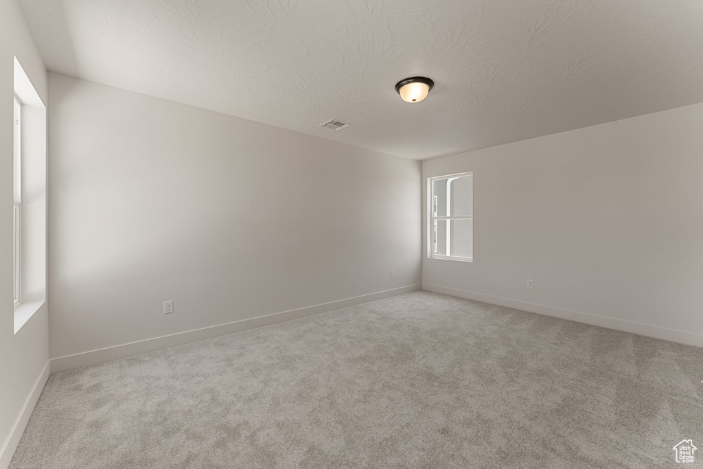 Spare room with light colored carpet and a textured ceiling
